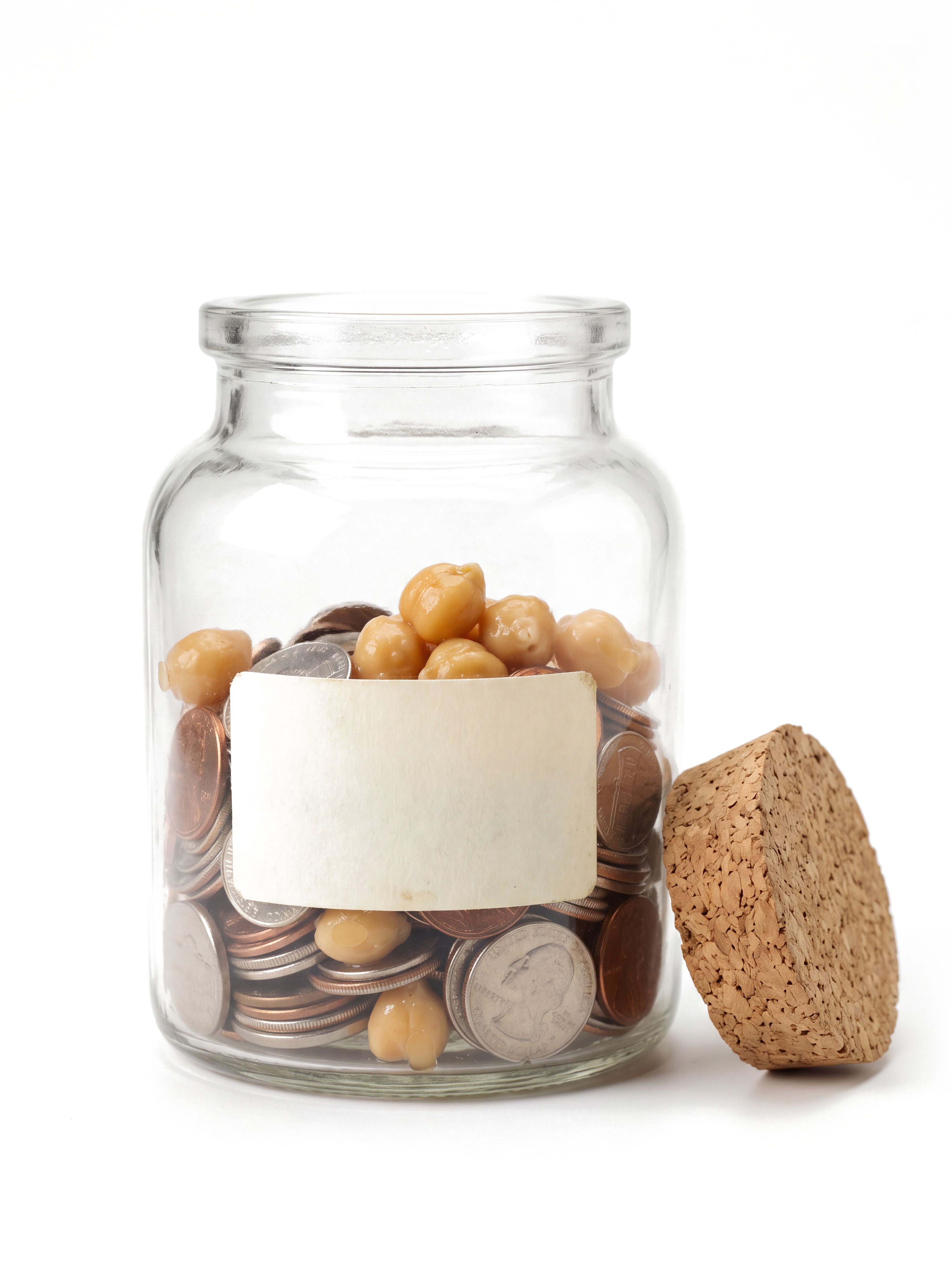 A glass jar holding coins and several garbanzo beans, with its cork beside it
